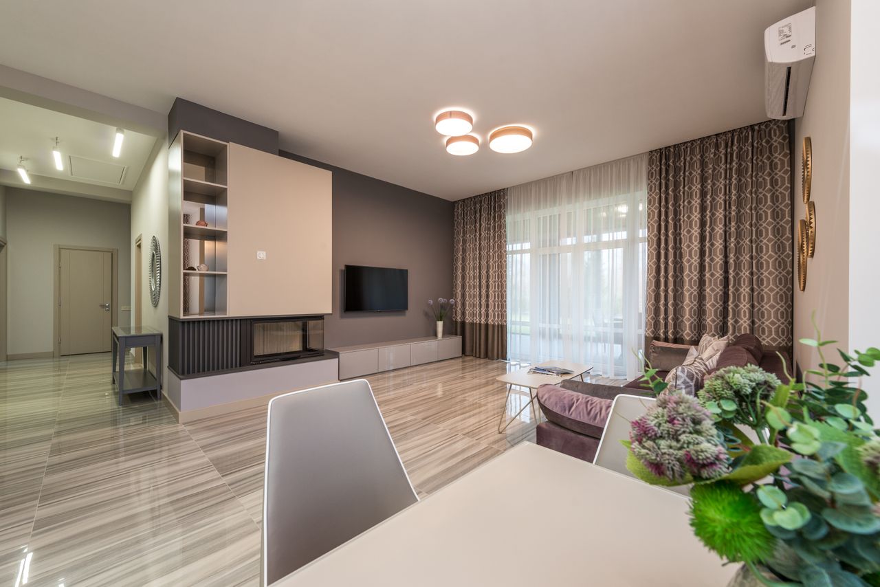 Spacious flat with sofa placed opposite TV set in living room with table decorated with flowers